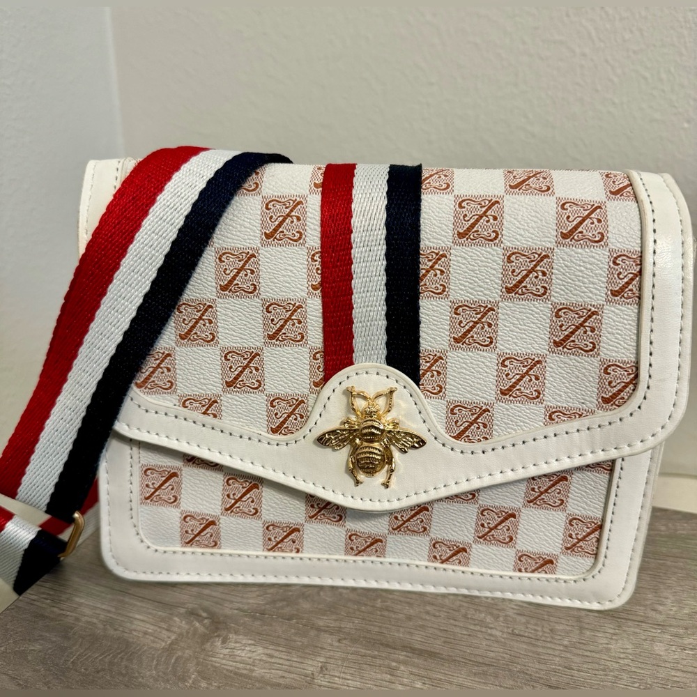 A stylish white monogrammed cross-body bag with an elegant bee design for women